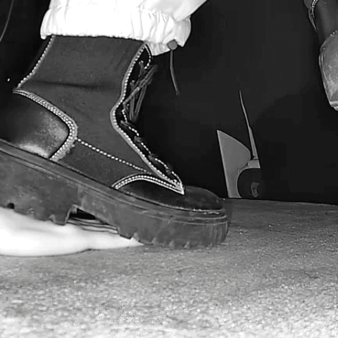 Girl candid steps on hand with chunky-heeled black ankle boots in the cinema