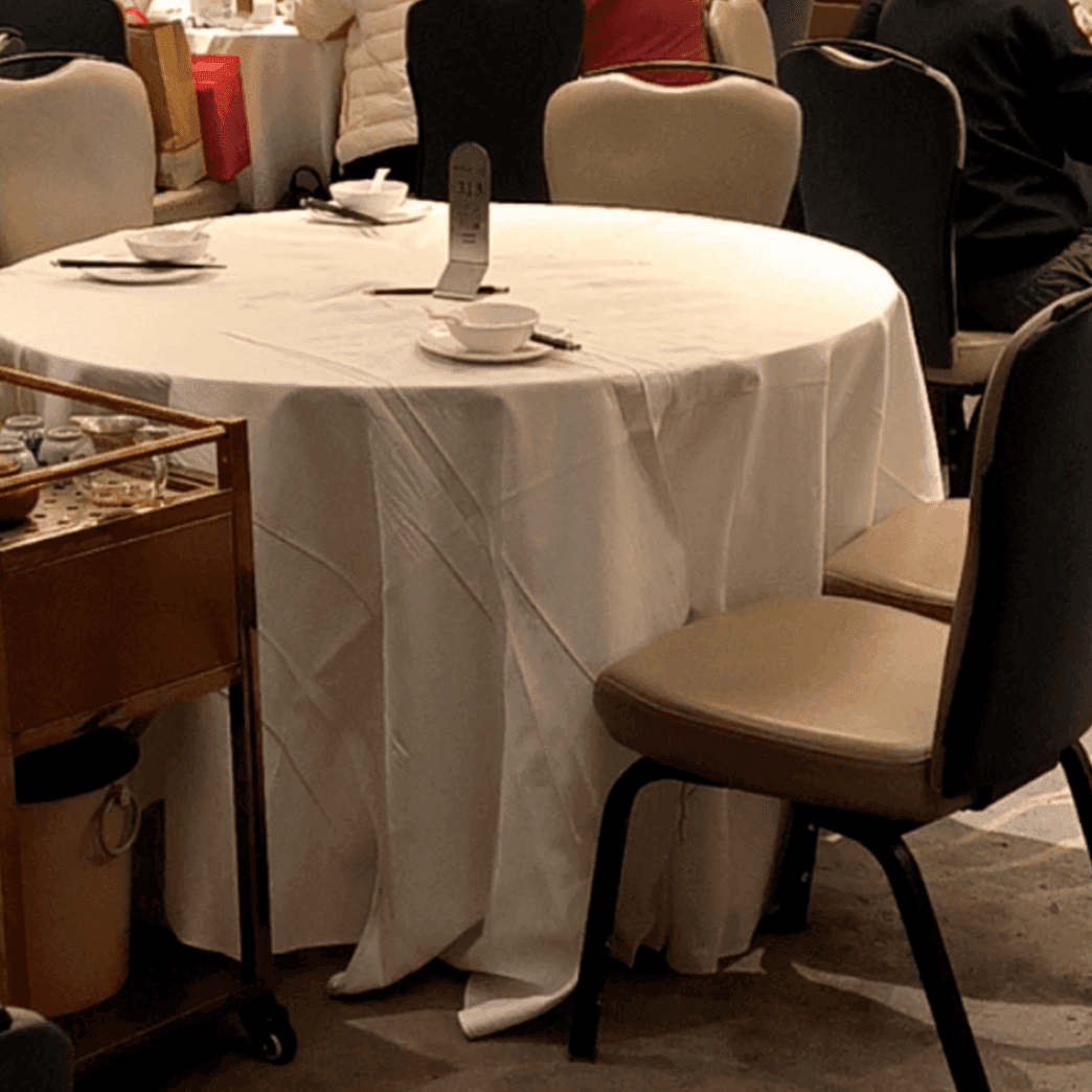 Girl candid steps on hand with her cute black leather shoes under the table