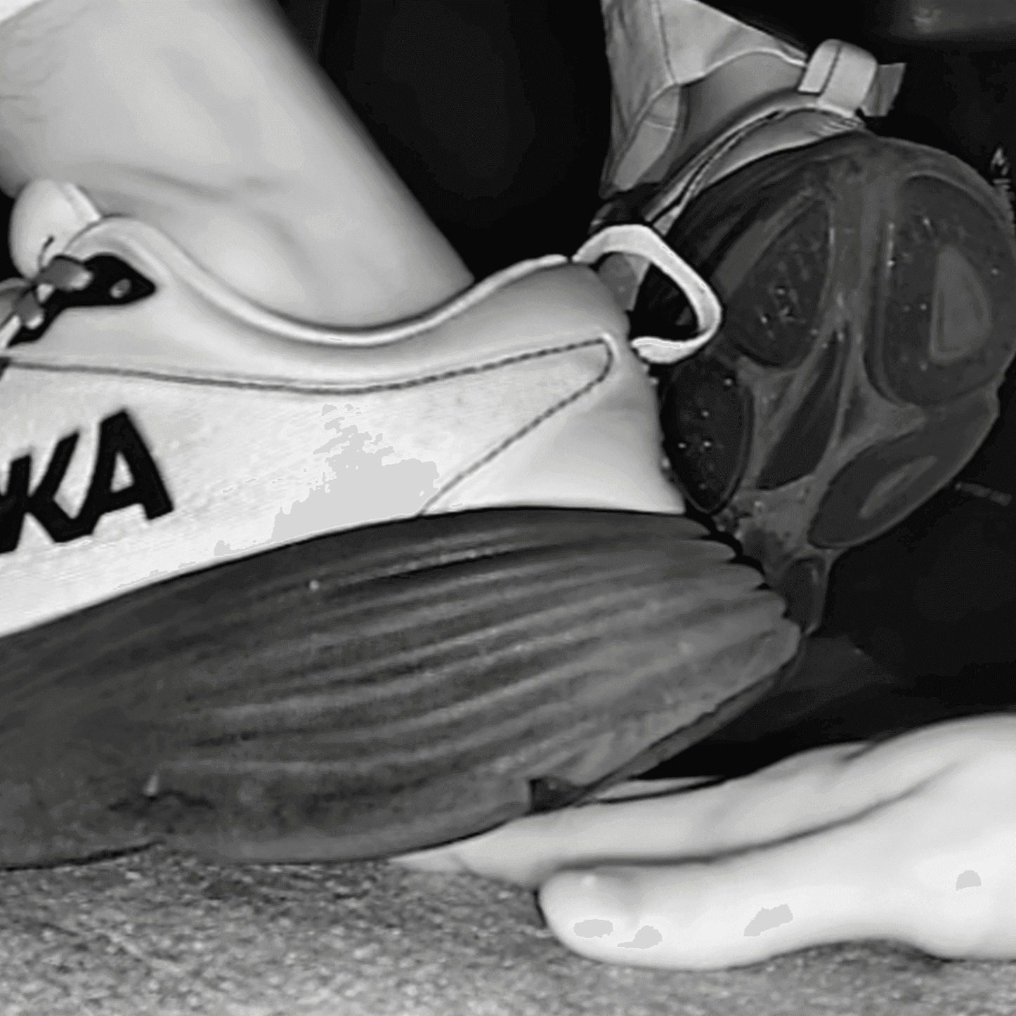 Woman candid hand trample with Hoka sneakers and black sandals at the cinema