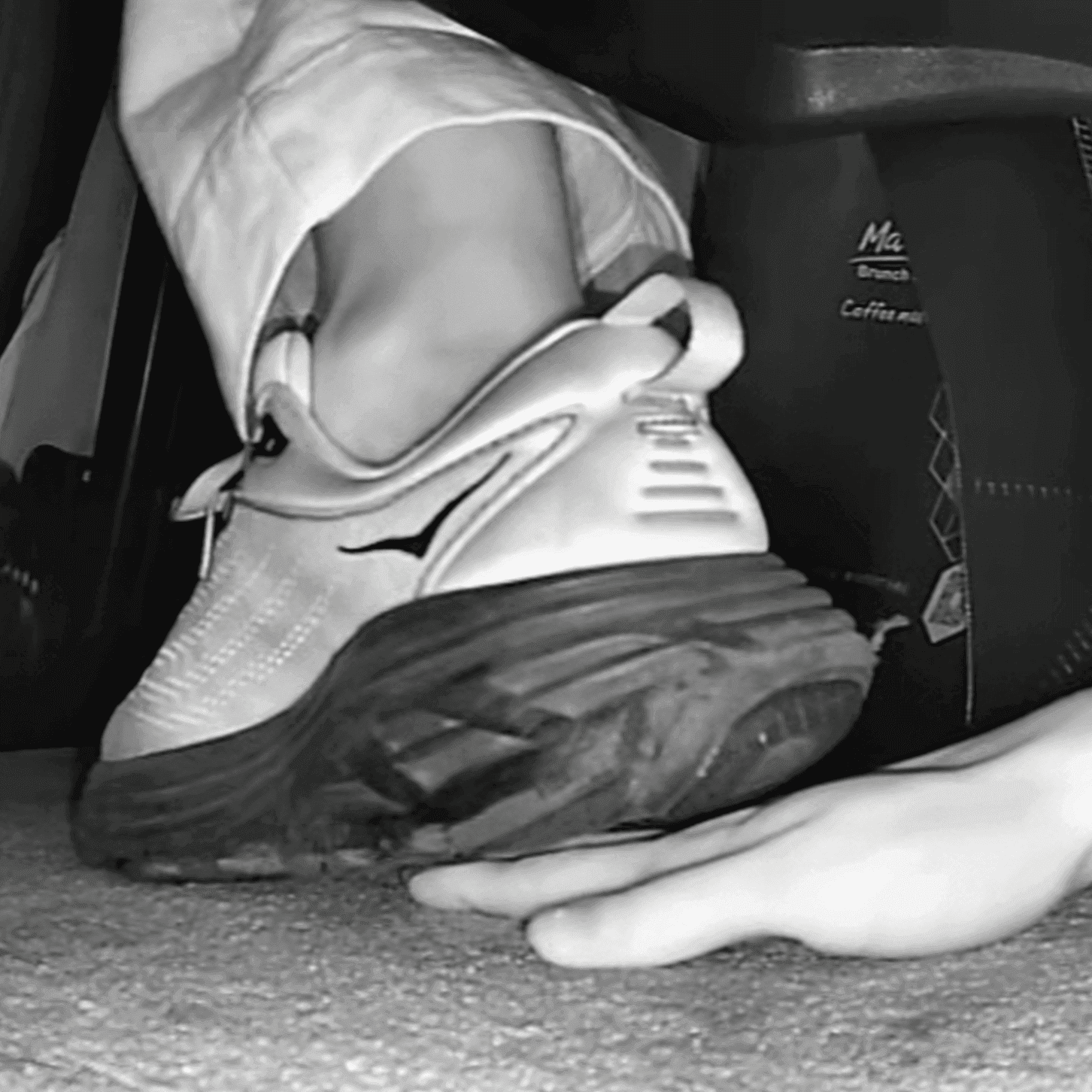 Woman candid hand trample with Hoka sneakers and black sandals at the cinema