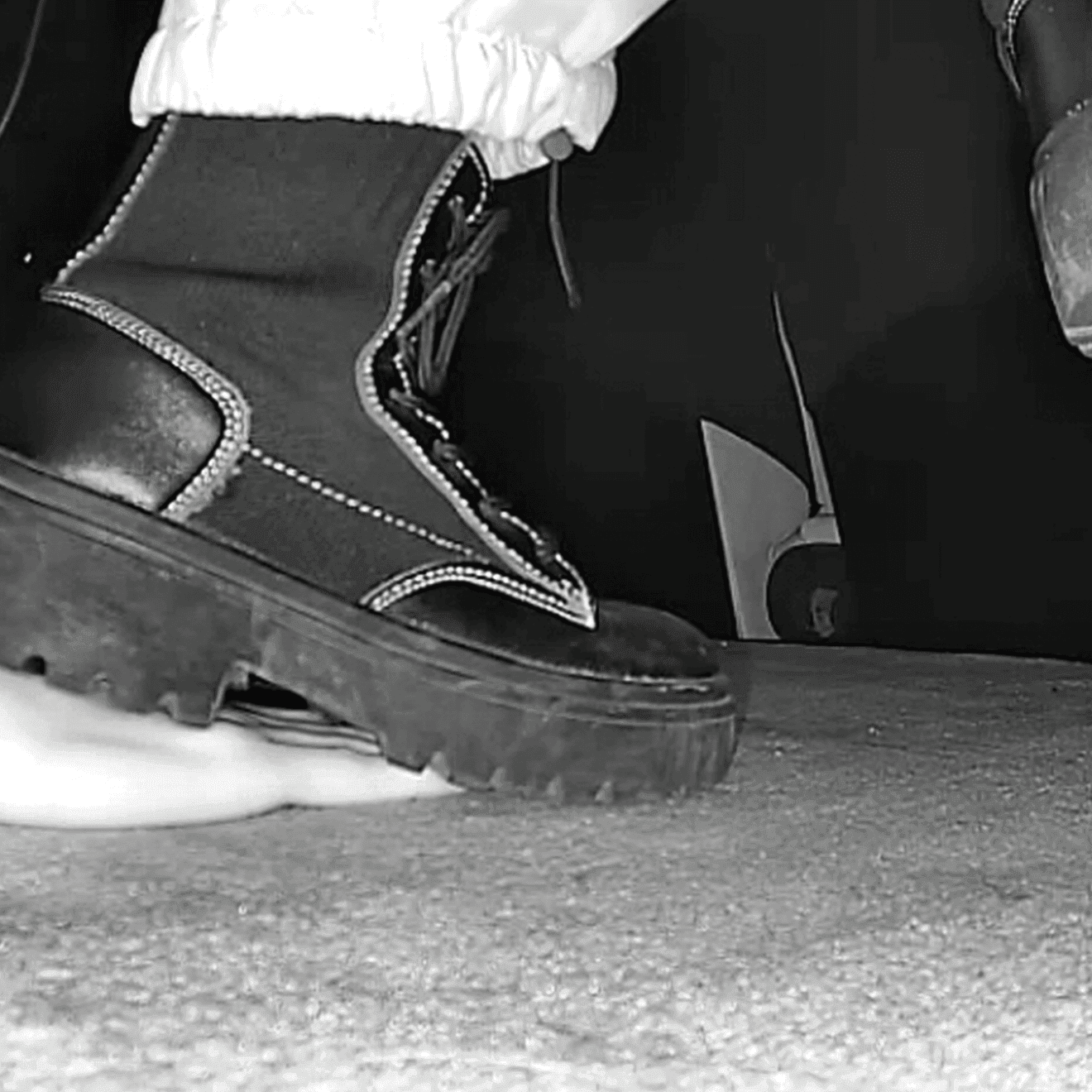 Girl candid steps on hand with chunky-heeled black ankle boots in the cinema
