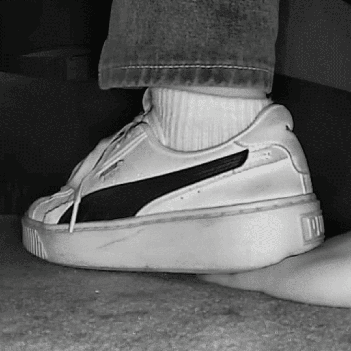 Girl candid hand trample with white socks Puma skate shoes in cinema